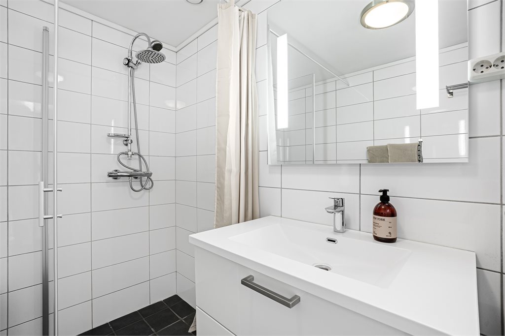 Det er innredet med vegghengt toalett, dusjhjørne og flott servant med speil.