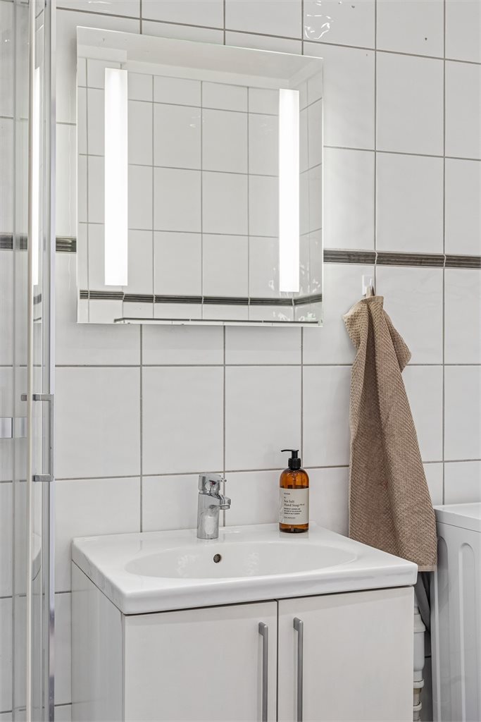Praktisk baderomsinnredning med speilskap og belysning.