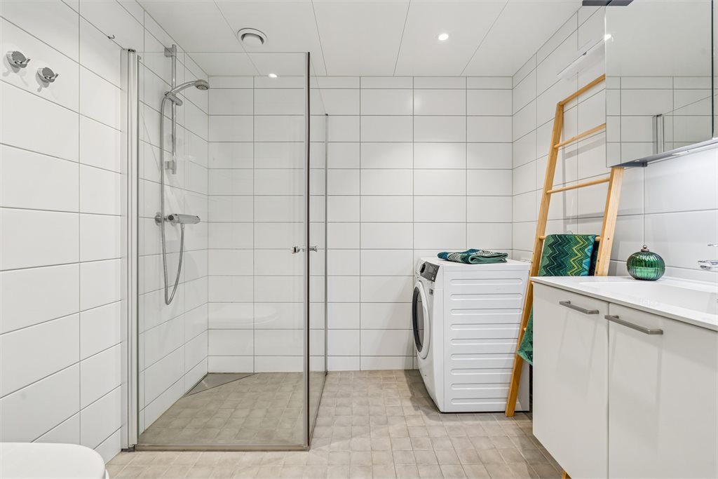 Lyst og stilrent baderom med fliser på vegger og gulv. Opplev for vaskemaskin.