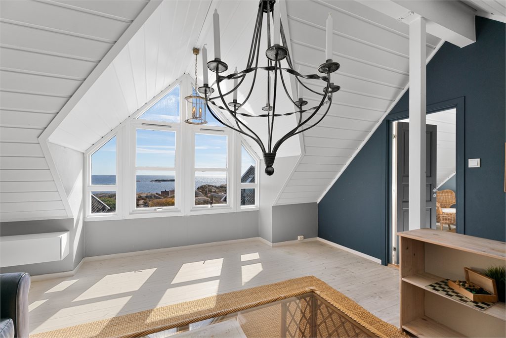 Loftstue med store vinduer og sjøutsikt.
