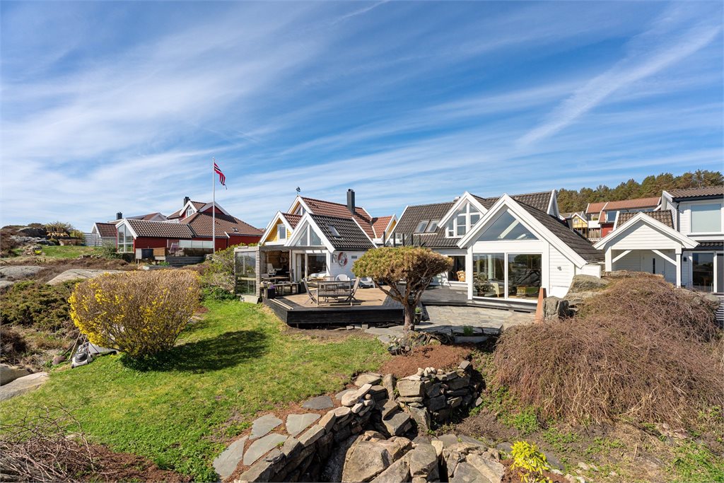 Solrik eiendom i maritimt kystlandskap med svaberg og sjøutsikt.
