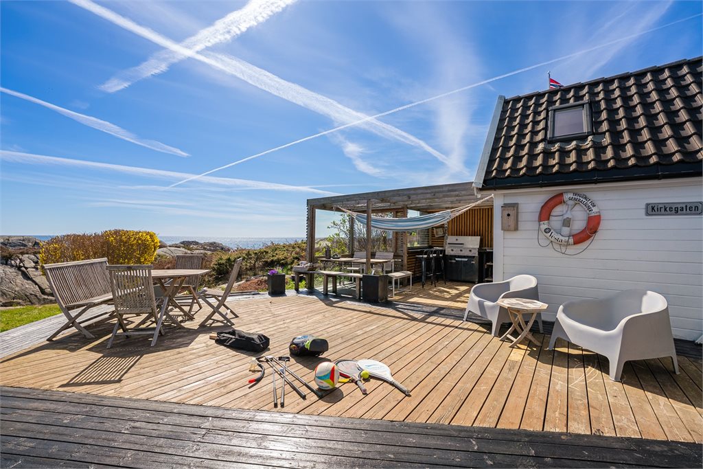 Stor uteplass med havutsikt og sommerstemning.
