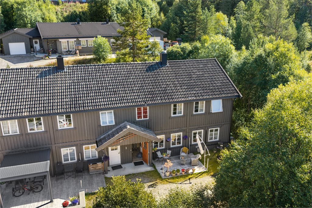 Oversiktsbilde av eiendommen med hyggelig uteplass og naturskjermet beliggenhet