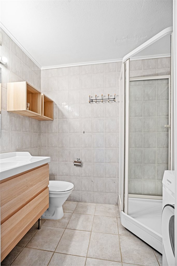 Lyst baderom med dusj og opplegg for vaskemaskin