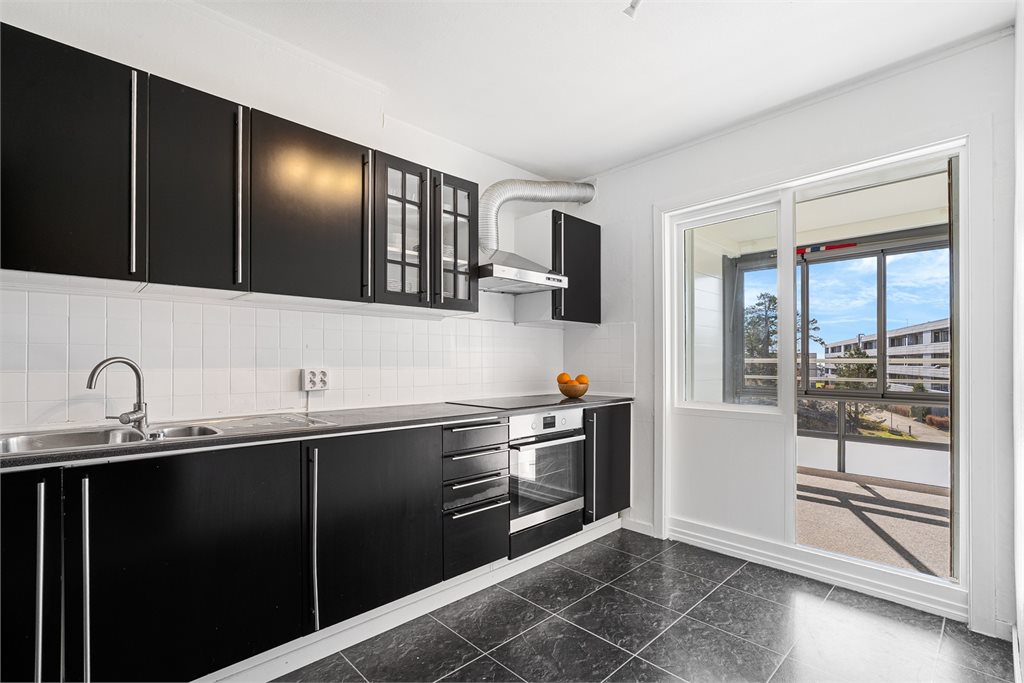 Praktisk kjøkken med utgang til innglasset balkong.