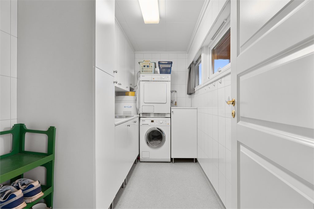 Praktisk vaskerom med god skapplass og opplegg for vaskesøyle
