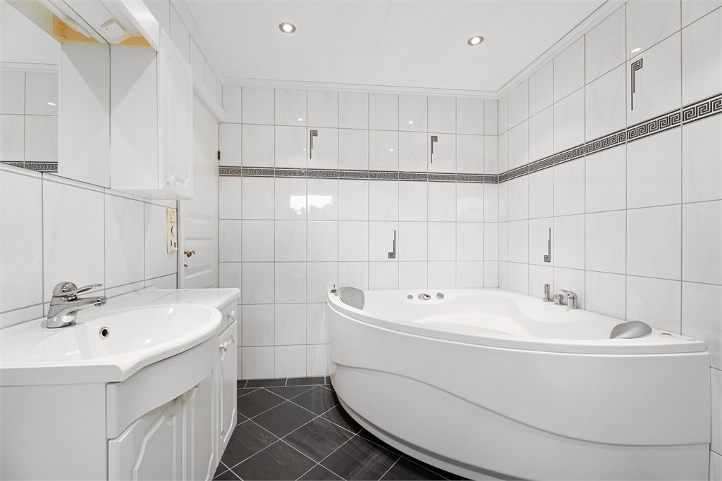 Romslig bad med hjørnebadekar og servant
