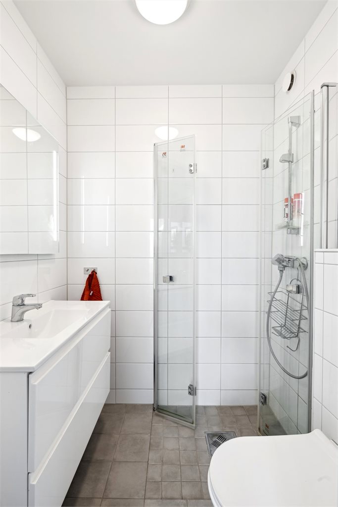 Badet flislagt og plassbesparende dusjdører.