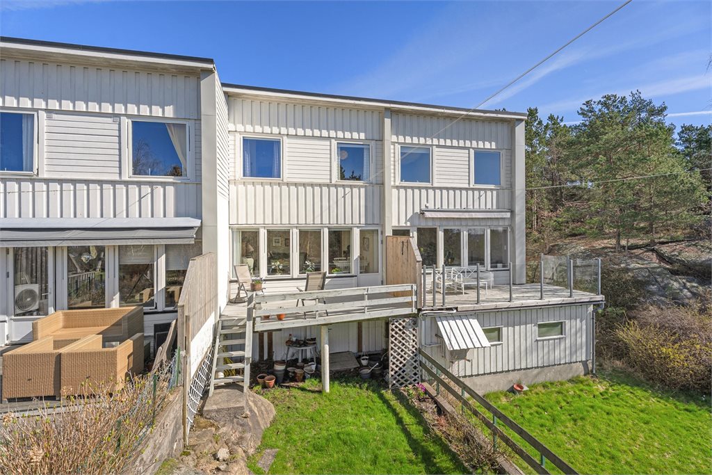 Boligens bakside med veranda, uteplass og grønne omgivelser