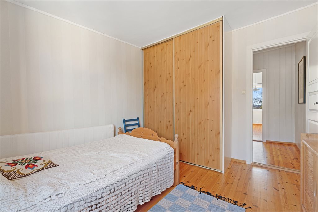 Soverom med tregulv og stor skyvedørsgarderobe som gir god oppbevaringsplass