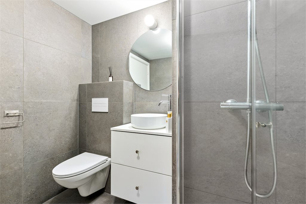 Delikat baderom med mørke og store fliser.