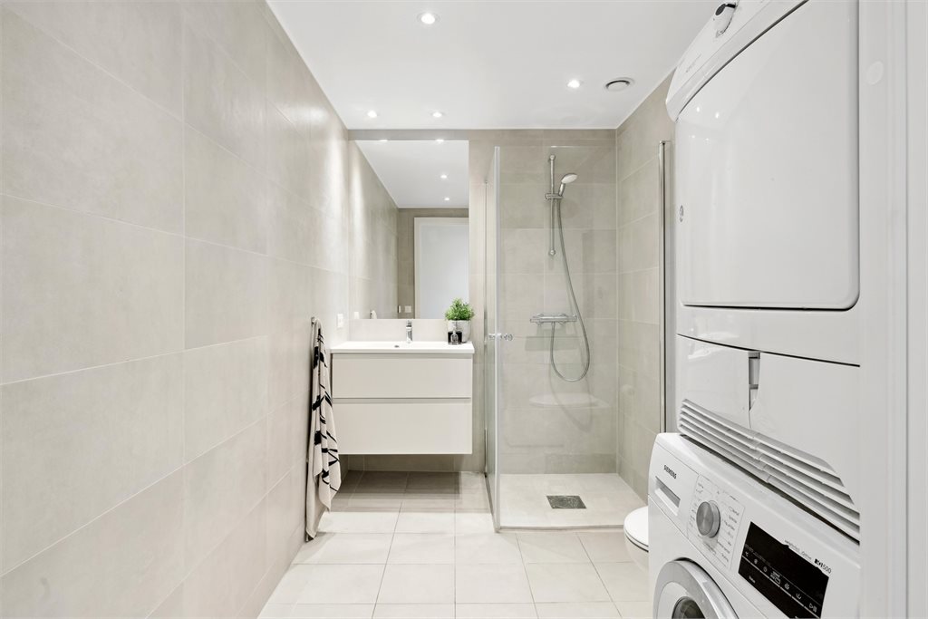 Flislagt baderom med opplegg for vaskemaskin.