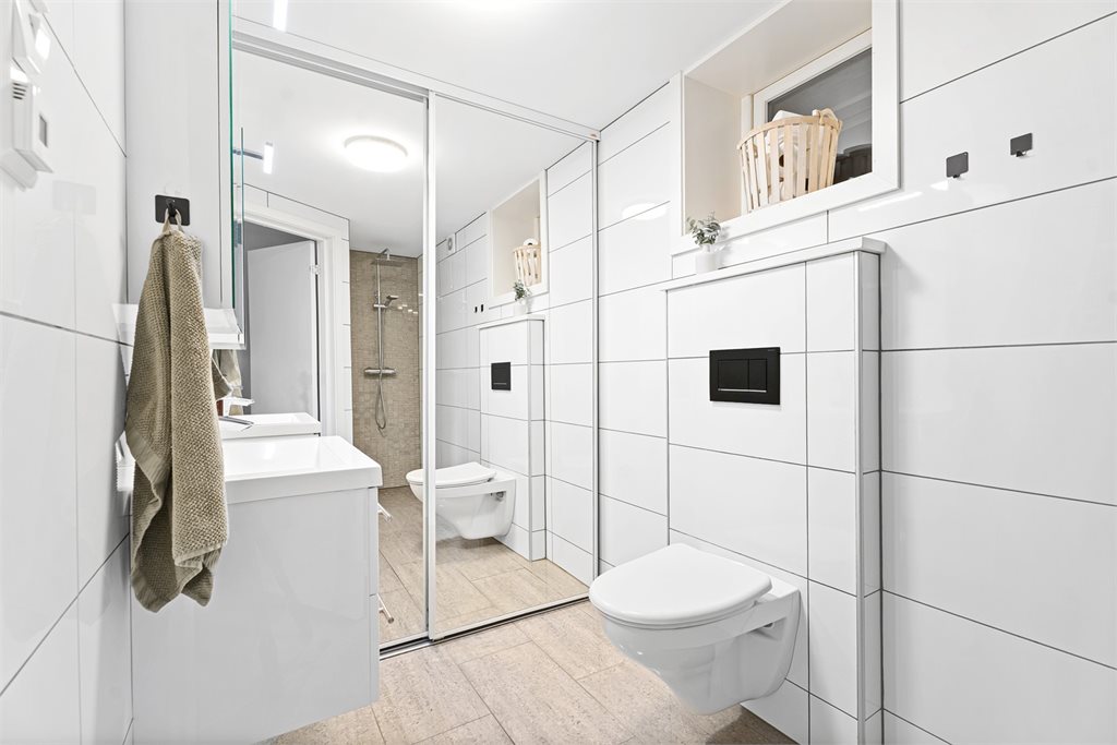 Badet i 1.etg er flislagt i tidløse fliser og innredet med en flott servant.