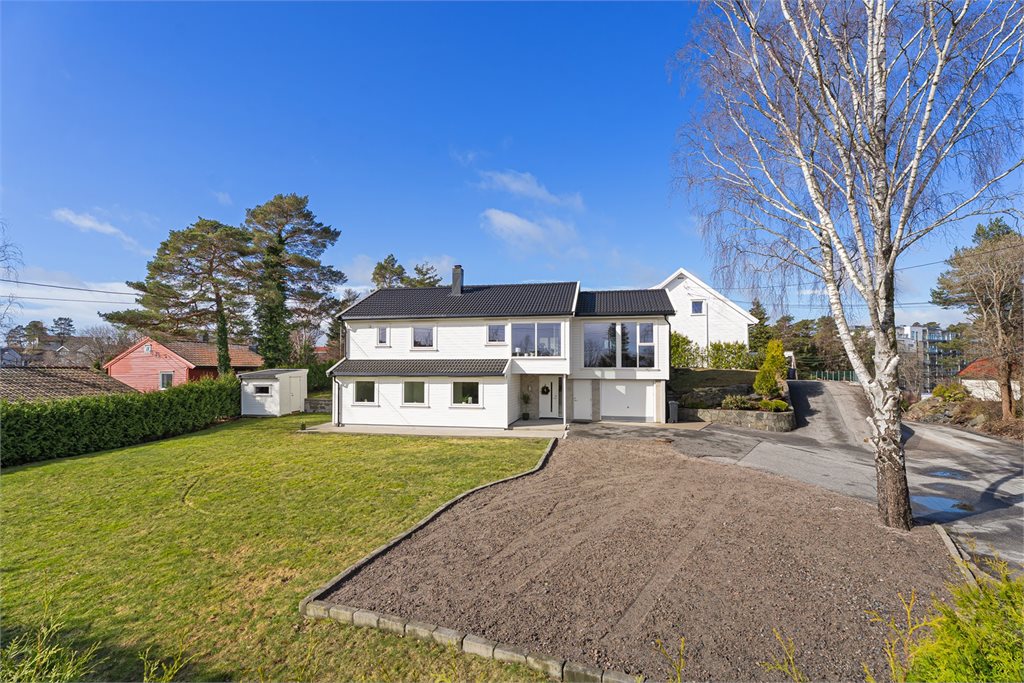 Pen fasade omgitt av stor tomt med gode muligheter.