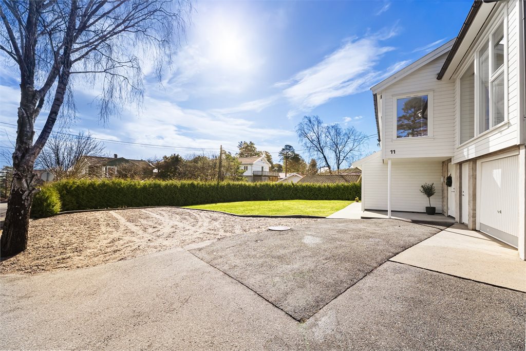 Romslig adkomst på fremsiden av huset, med garasje og en stor innbydende hage.
