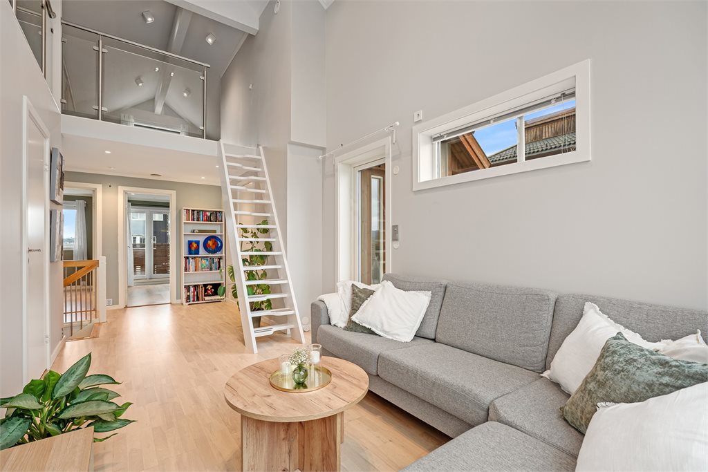 Stue med åpen løsning og elegant trappeløsning
