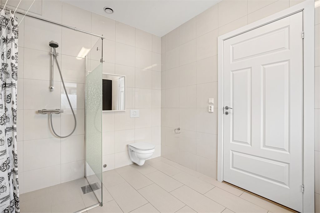 Stilrent bad med dusjløsning og vegghengt toalett
