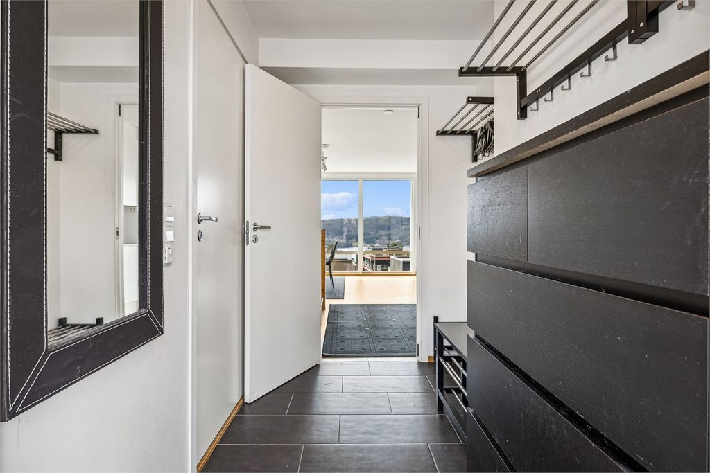 Lys entrè med fliser på gulv med varme i gulv. Her er det god plass til å henge fra seg yttertøy.