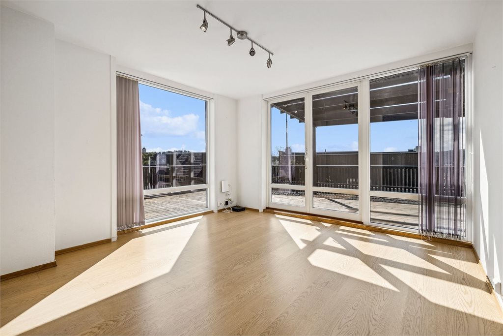 Lys stue i underetasjen med flere store vindusflater.