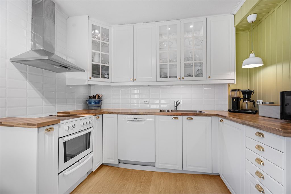 Kjøkkenet er en tidløs innredning med hvite profilerte fronter.