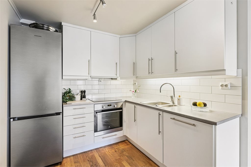 Kjøkkenet har praktisk form med godt med skap- og oppbevaringsplass.