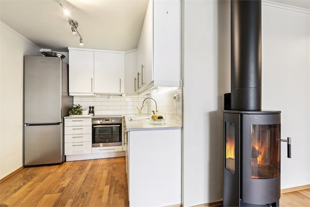 Kjøkkenet er innredet med slette lyse fronter. Fliser på benken og god plass til oppbevaring