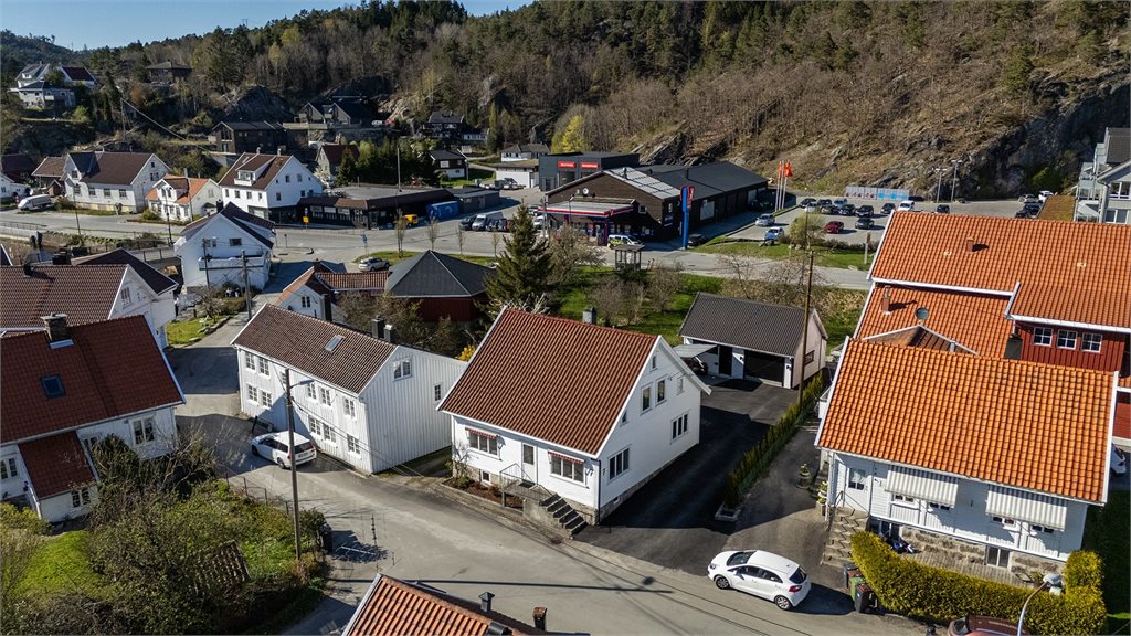 Dronebilde som viser boligen i etablert boligområde med umiddelbar nærhet til butikk mm