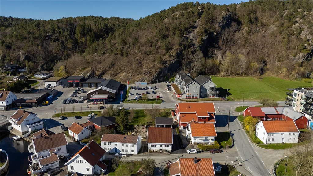 Dronebilde som viser nærliggende servicetilbud, boligbebyggelse og kort avstand til butikk, slakter mm