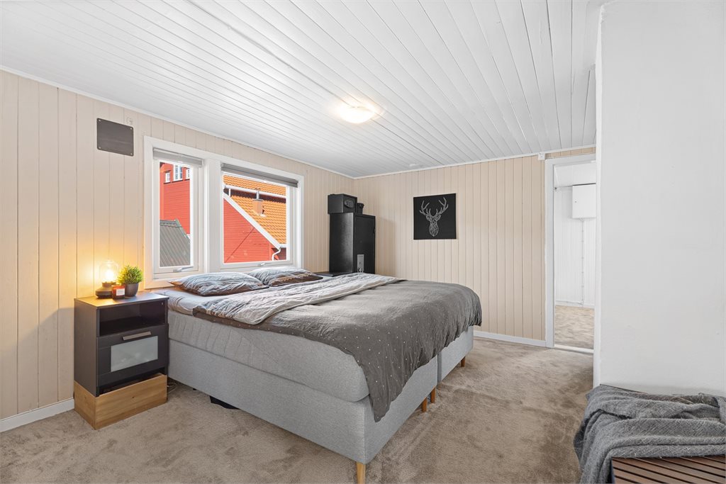Romslig hovedsoverom med plass til dobbeltseng, garderobe og naturlig lys fra vinduer