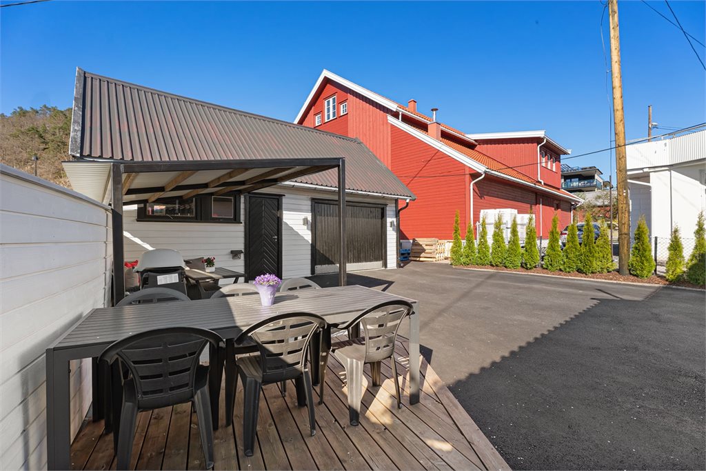Solrik uteplass med platting, sittegruppe og god plass til parkering