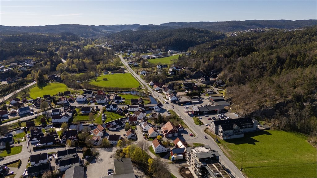 Vidstrakt oversiktsbilde som viser området med variert bebyggelse, grønne omgivelser og gode forbindelser til nærliggende veier og servicetilbud
