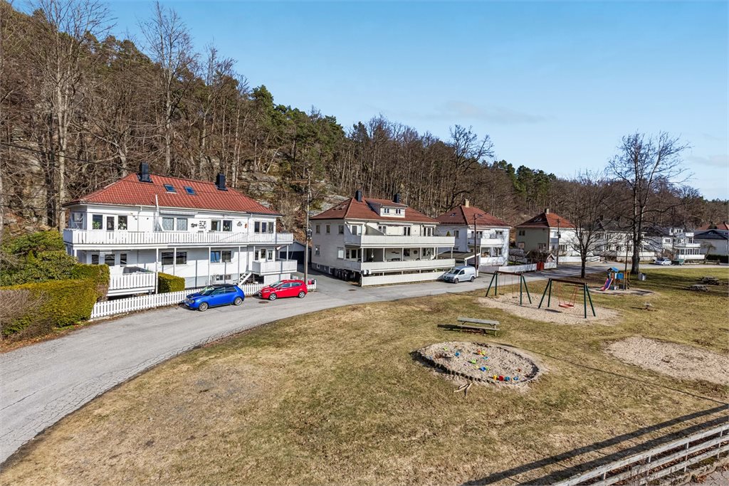 Oversiktsbilde av nærområdet med lekeplass og boligen i bakgrunnen