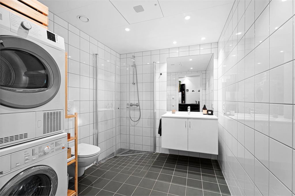 Innredet med flott servant med speil, hjørnedusj og vegghengt toalett. God plass til både vask og tørk. 