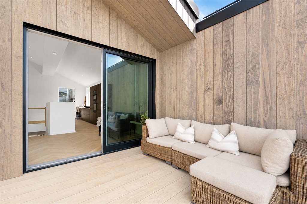 Sømløs overgang mellom stue og terrasse via store skyvedører.