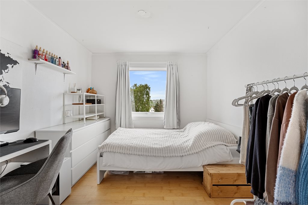 Lyst og romslig soverom med store vinduer og god plass til både seng, skrivebord og oppbevaring