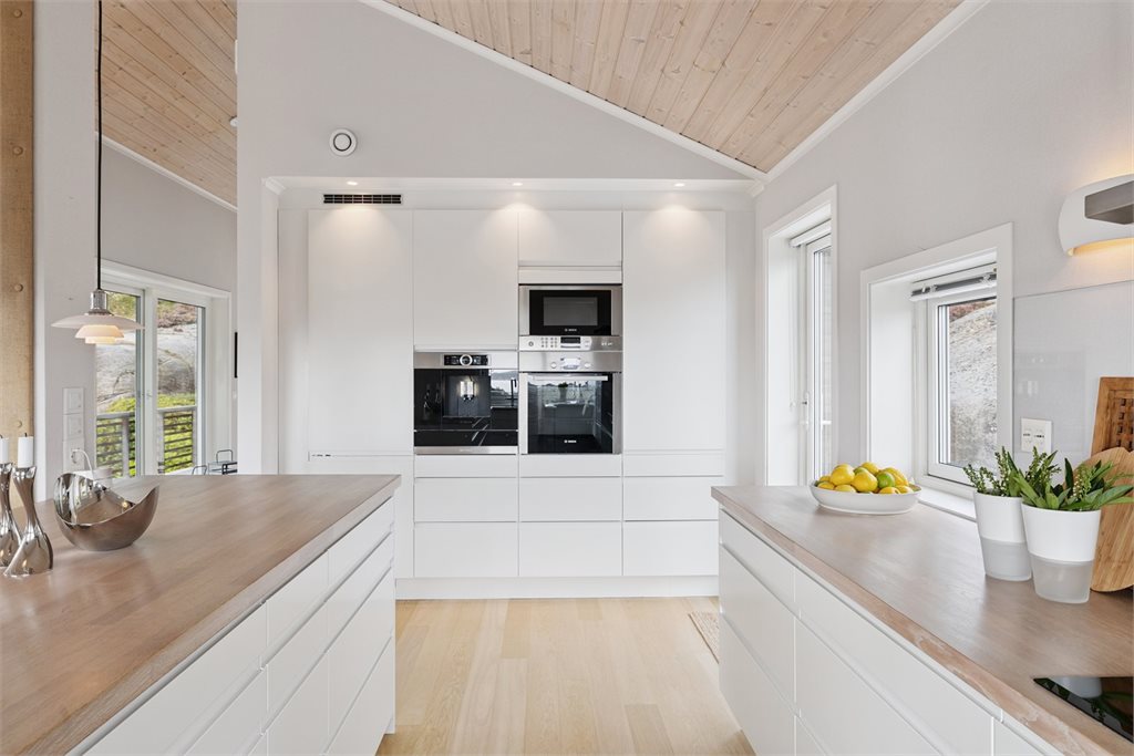 Stilfullt kjøkken med integrerte hvitevarer som kaffemaskin, varmeskuffe etc  