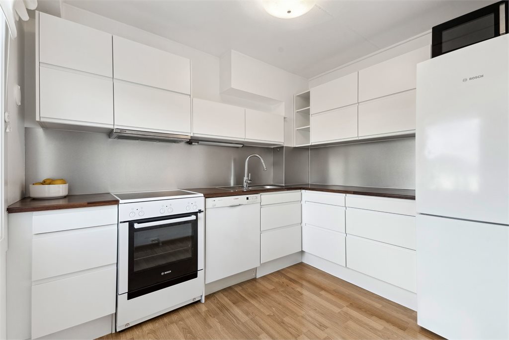 Kjøkkenet har lyse fronter, stor arbeidsbenk og godt med oppbevaring i skap.