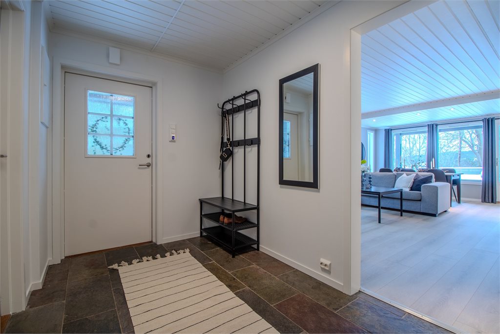 Romslig entré med flislagt gulv og praktisk plass for sko og yttertøy.