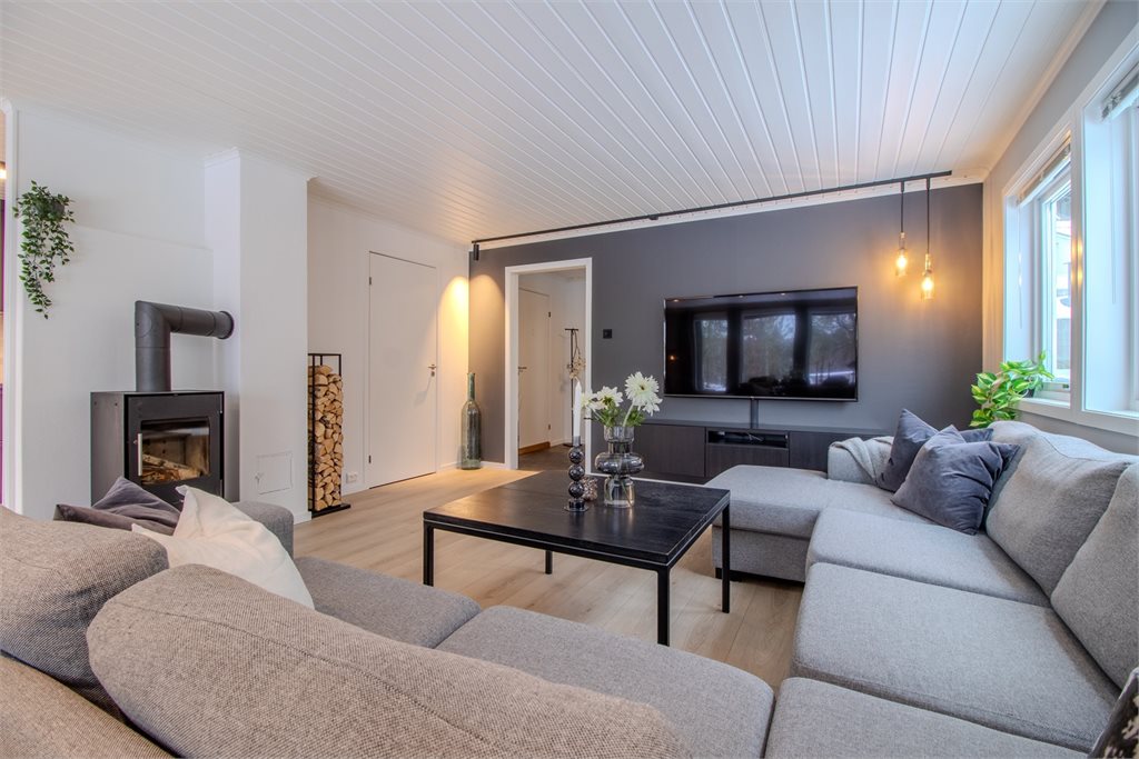 Stuen har en lun atmosfære, moderne fargevalg og vedovn som varmer godt.