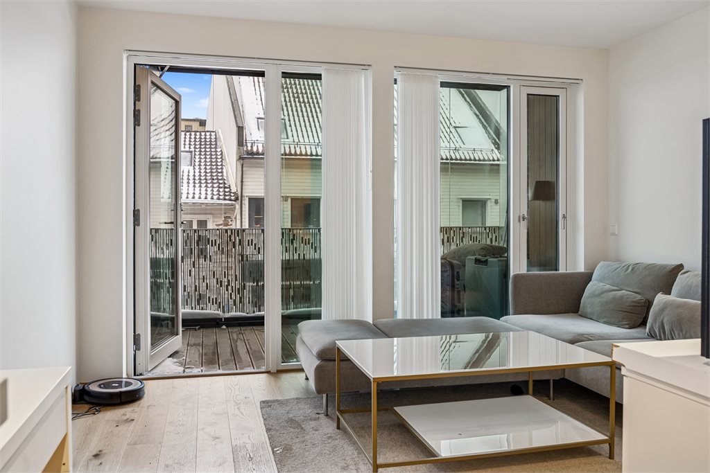 Romslig stue med utgang til innglasset balkong, som oppleves som en forlengelse av stuen.