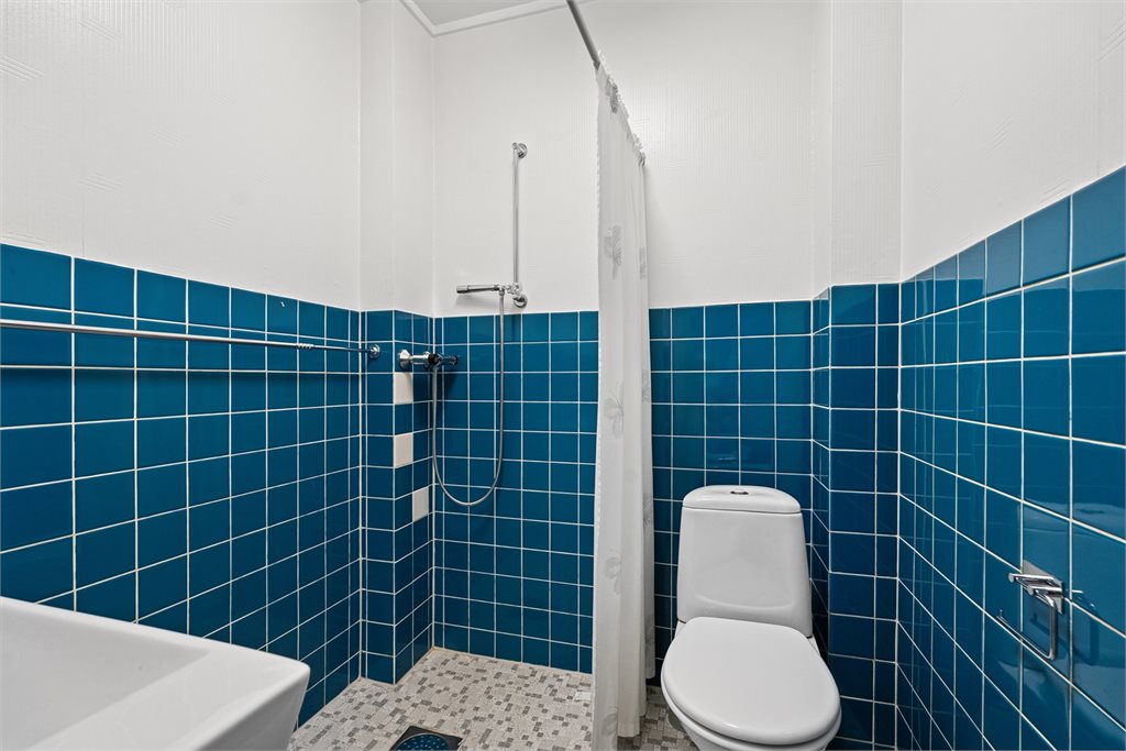 Flislagt baderom med dusj og toalett.