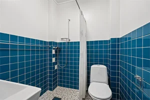 Flislagt baderom med dusj og toalett.