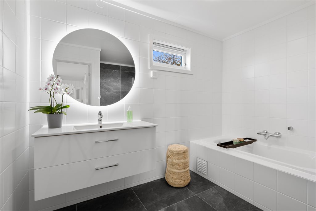 Badet er flislagt i tidløse fliser og innredet med en flott servant.