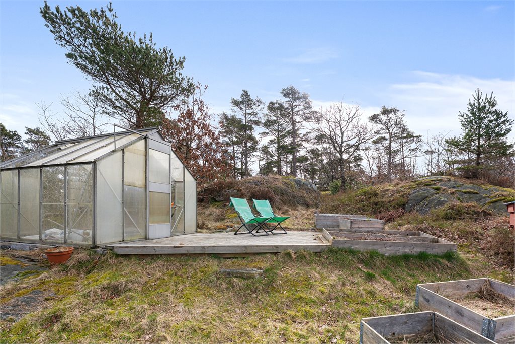Terrasse med drivhus og plass til sittegrupper.
