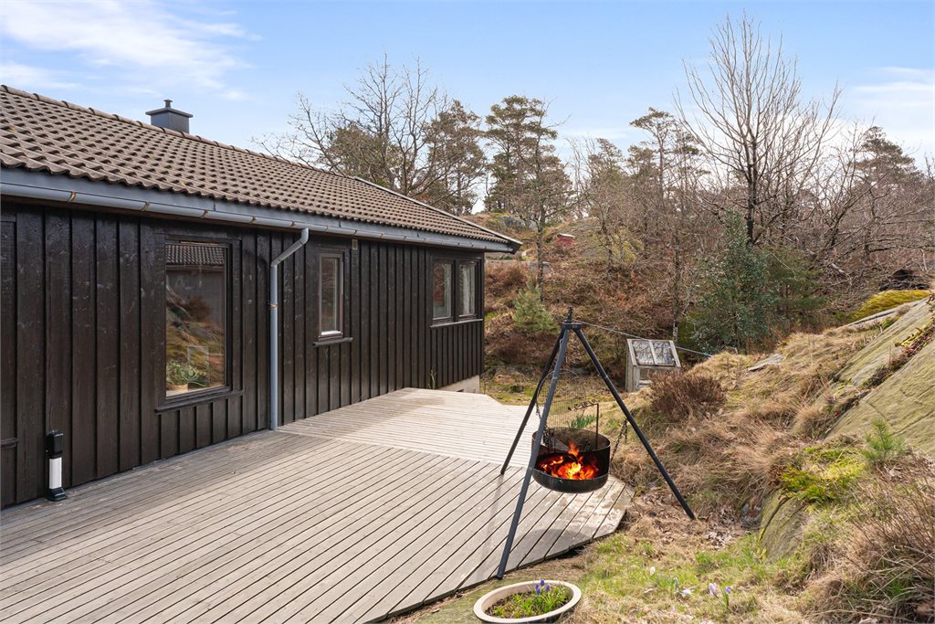 Solrik terrasse med utsyn mot grønne omgivelser.
