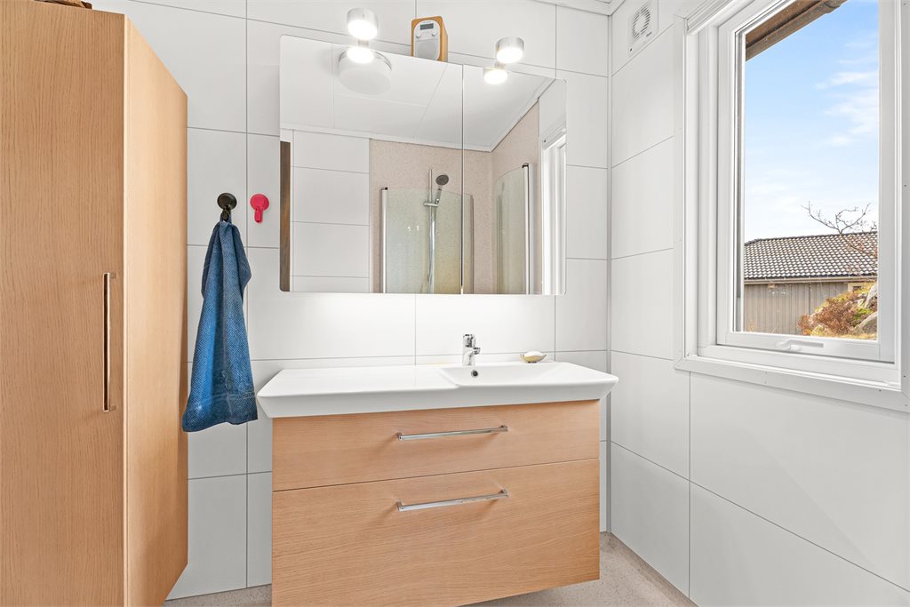 Moderne bad med servantinnredning og vindu.
