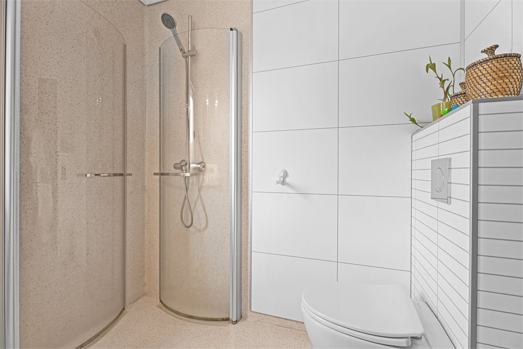 Bad med dusj og toalett i lyse, tidløse farger.
