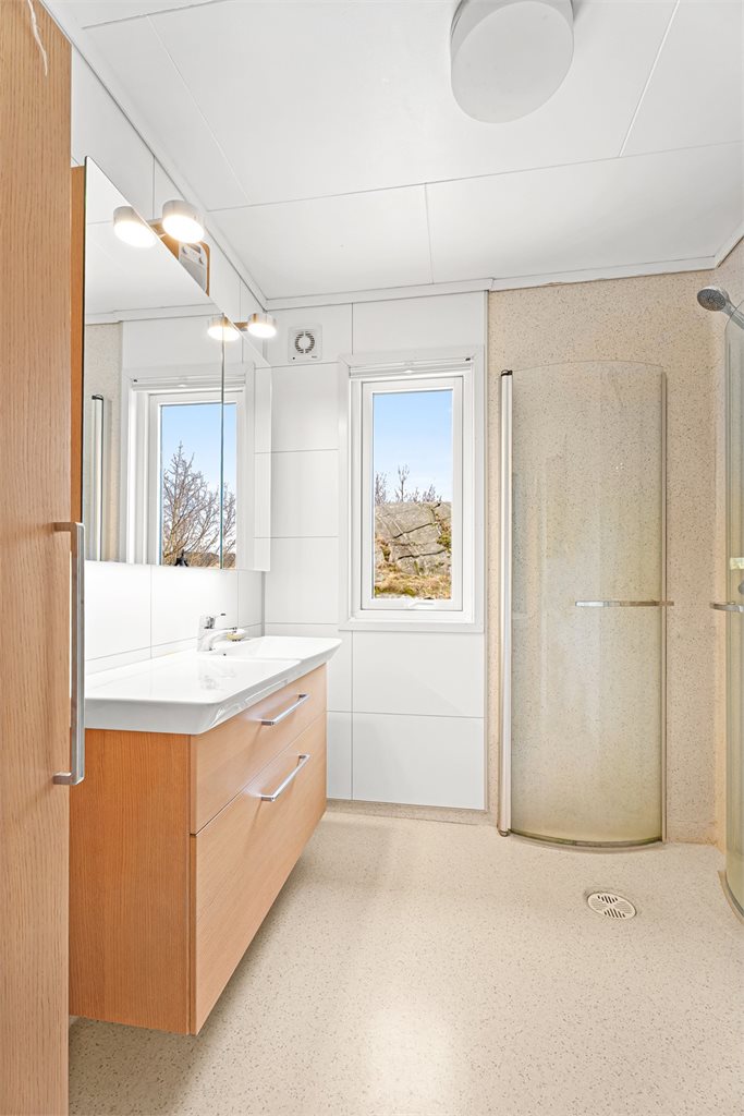 Bad med dusj og toalett i lyse, tidløse farger.
